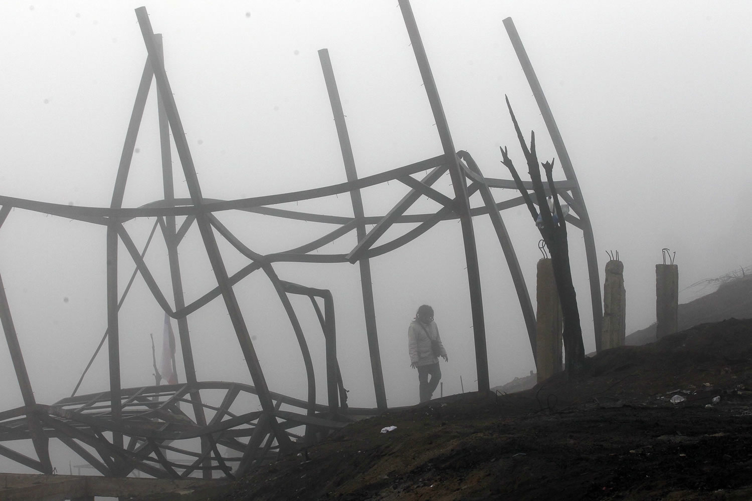 A woman walks Tuesday through the remains of a house destroyed by a wildfire in Valparaiso, Chile.