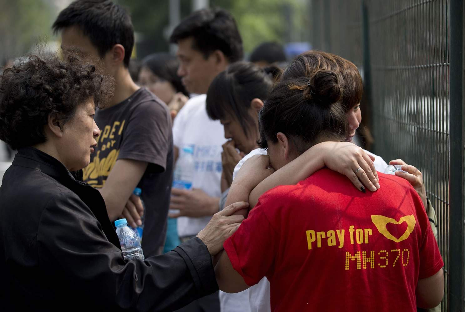 A woman, left, tries to comfort relatives of passengers on missing Malaysia Airlines Flight MH370 on Friday outside the Malaysian embassy in Beijing.