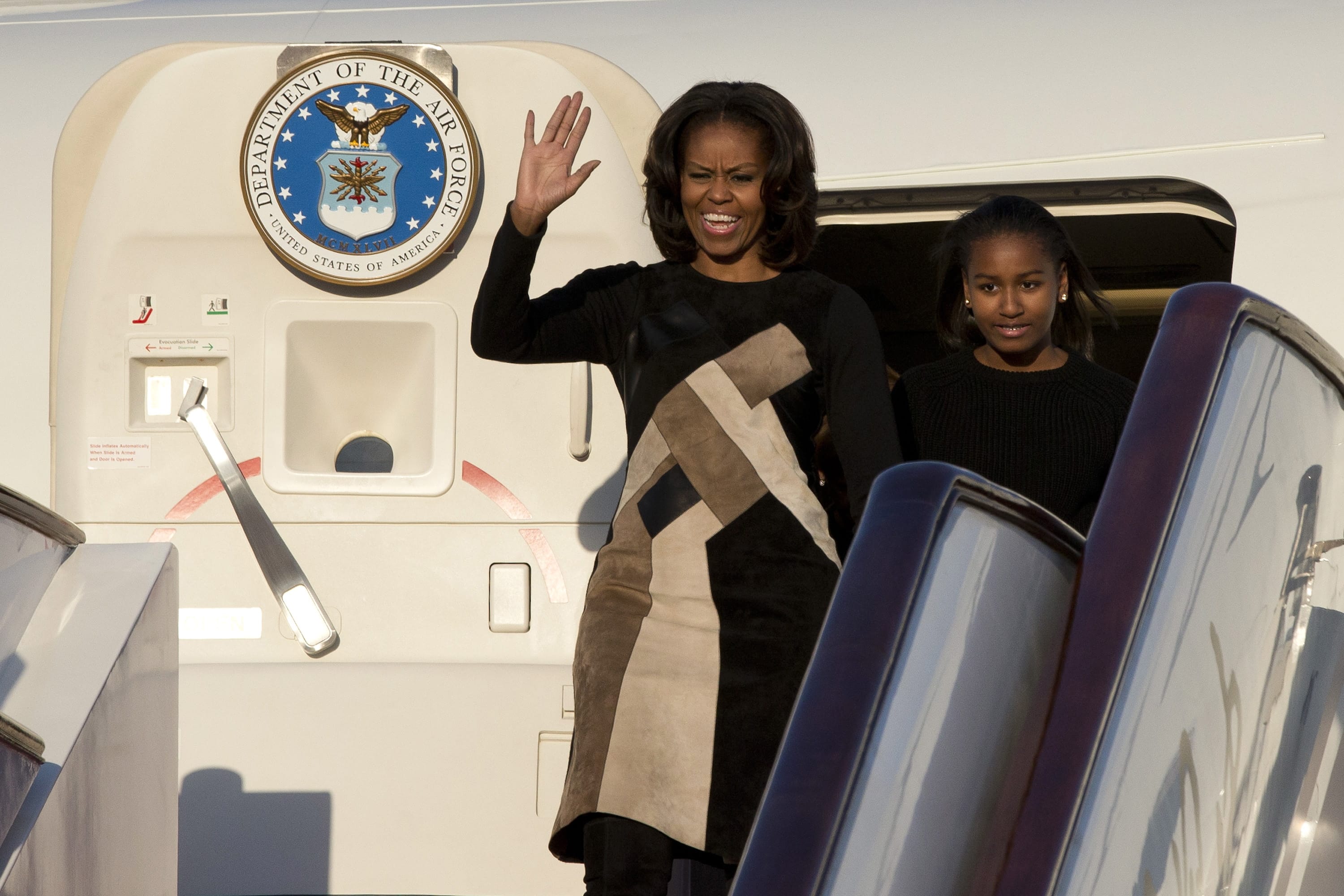 Michelle Obama waves as she and her daughter, Sasha, arrive at Capital International Airport in Beijing on Thursday.