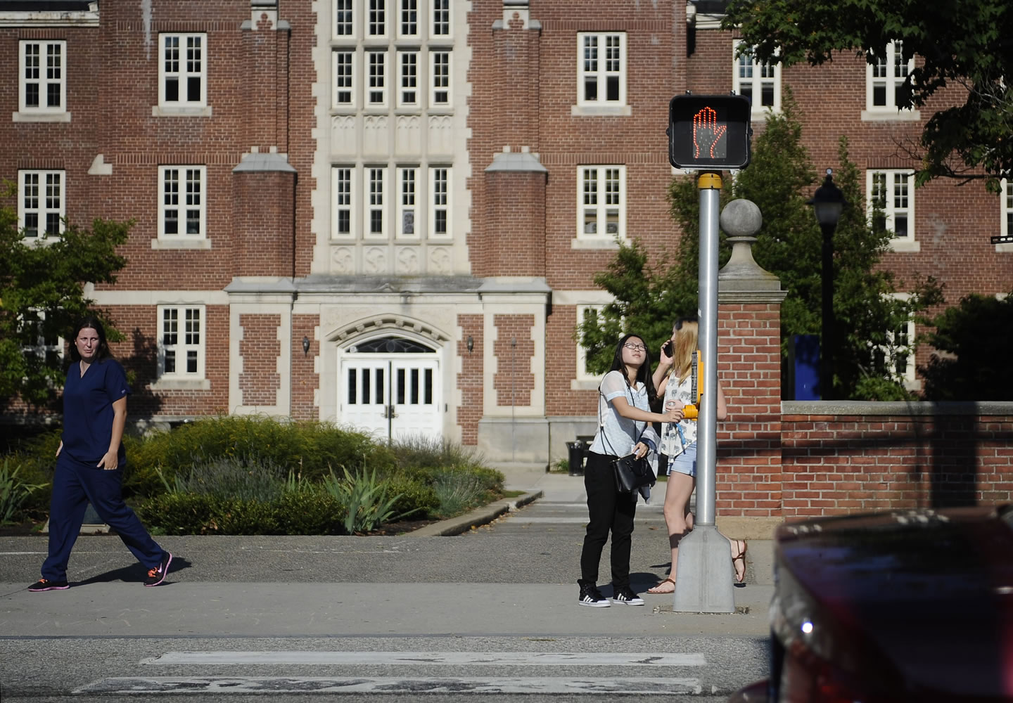University of Connecticut sophomore Anyi Yang of Beijing pushes a button at a crosswalk outside her dorm in Storrs, Conn. A surge of students from China is leading U.S. universities to confront the challenges of integrating them more into American campus life.