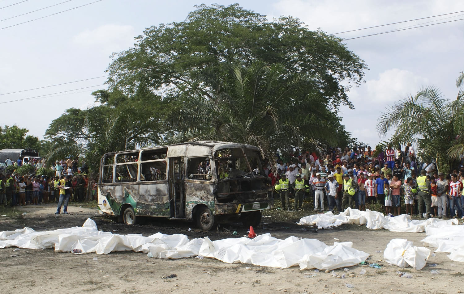 People gather around a burnt bus and bags containing the remains of children who where killed when their bus caught fire in Fundacion, in northern Colombia, Sunday, May 18, 2014. Colombian authorities have detained the driver of the overcrowded bus that burned, killing 32 children, the local mayor said Monday.