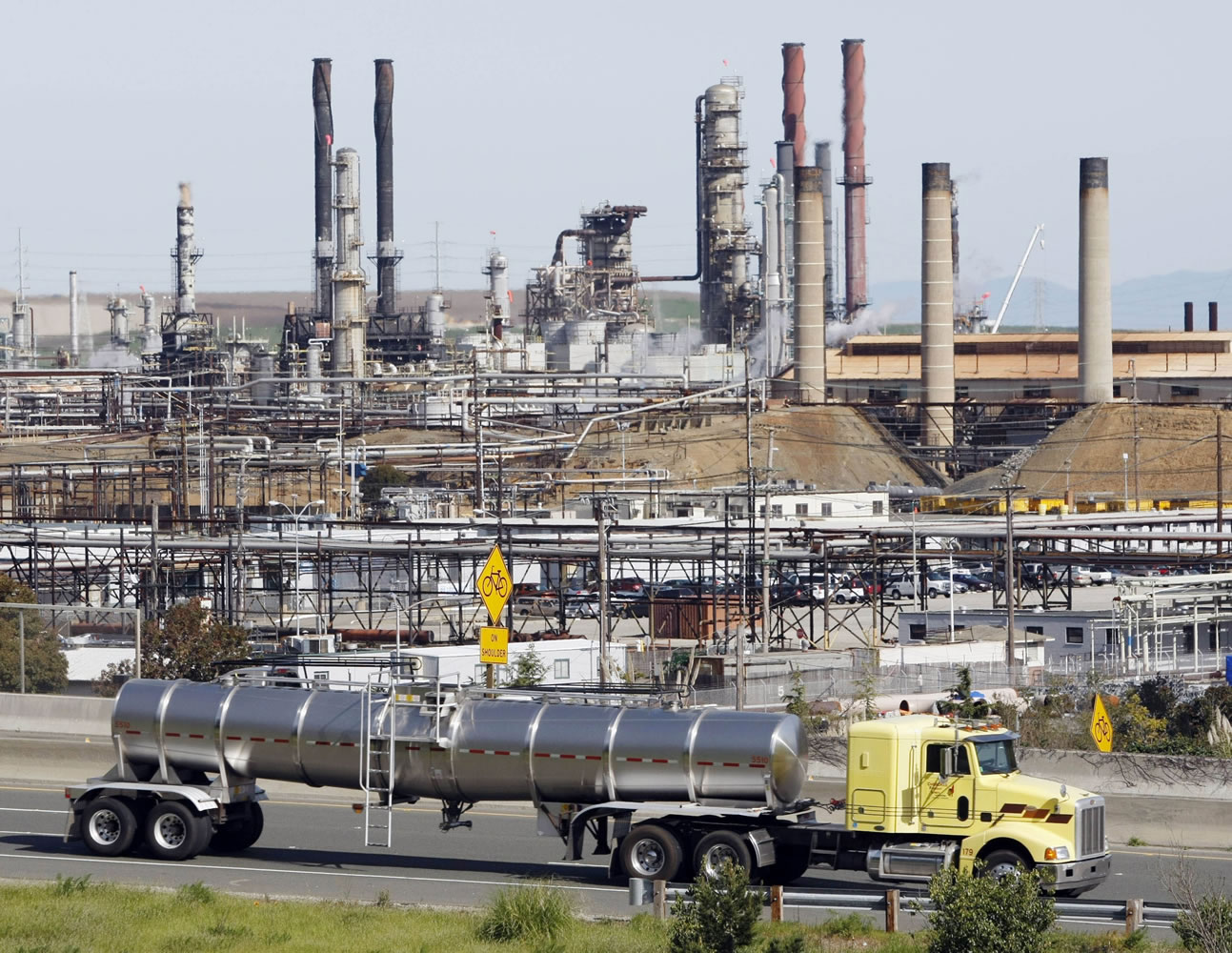 A tanker truck passes an oil refinery in Richmond, Calif. The Environmental Protection Agency announced new rules Tuesday to reduce toxic air pollution from oil refineries by forcing operators to adopt new technology that better monitors and controls emissions.