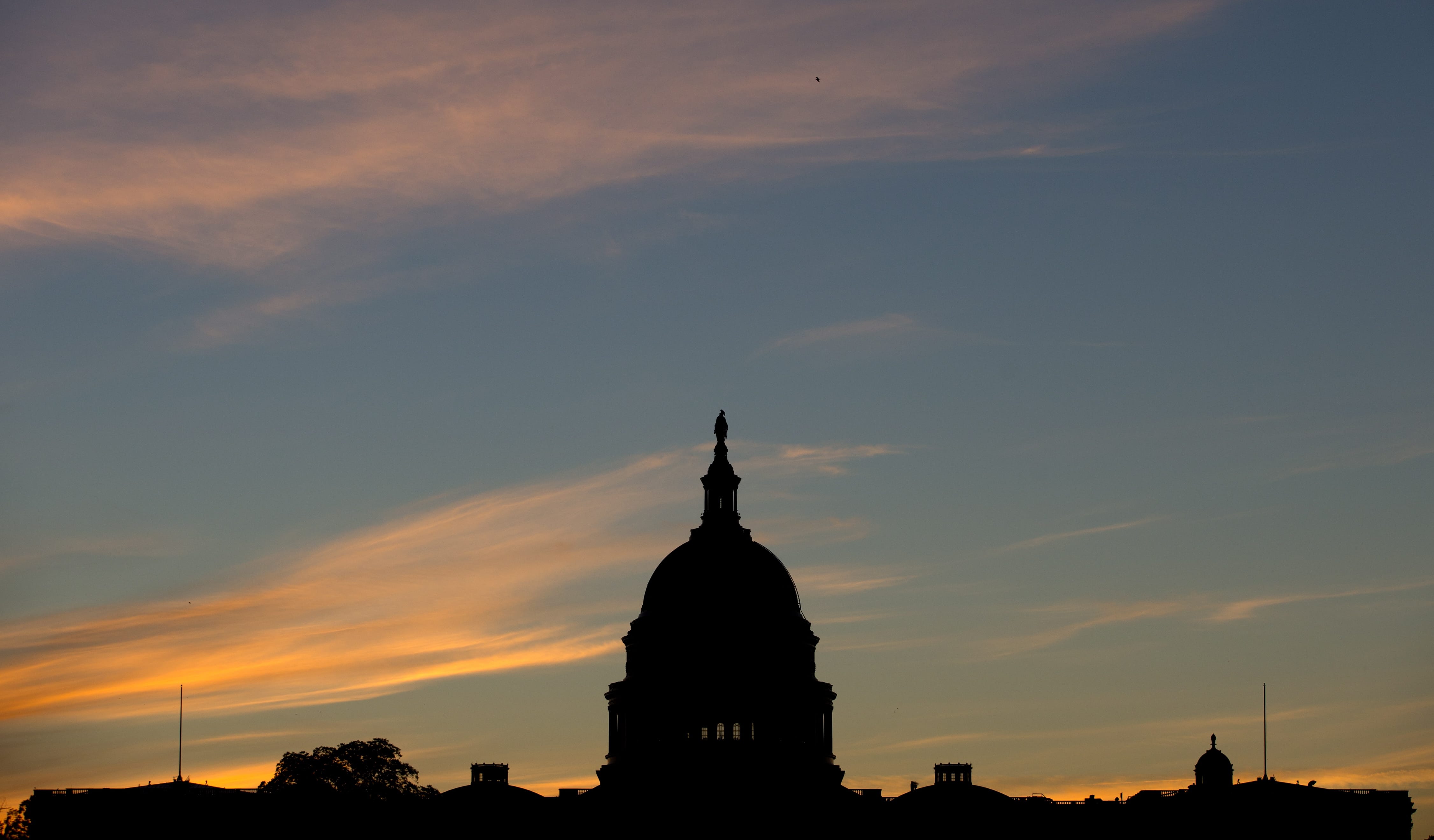 The U.S. Capitol dome is silhouetted by the sunrise.