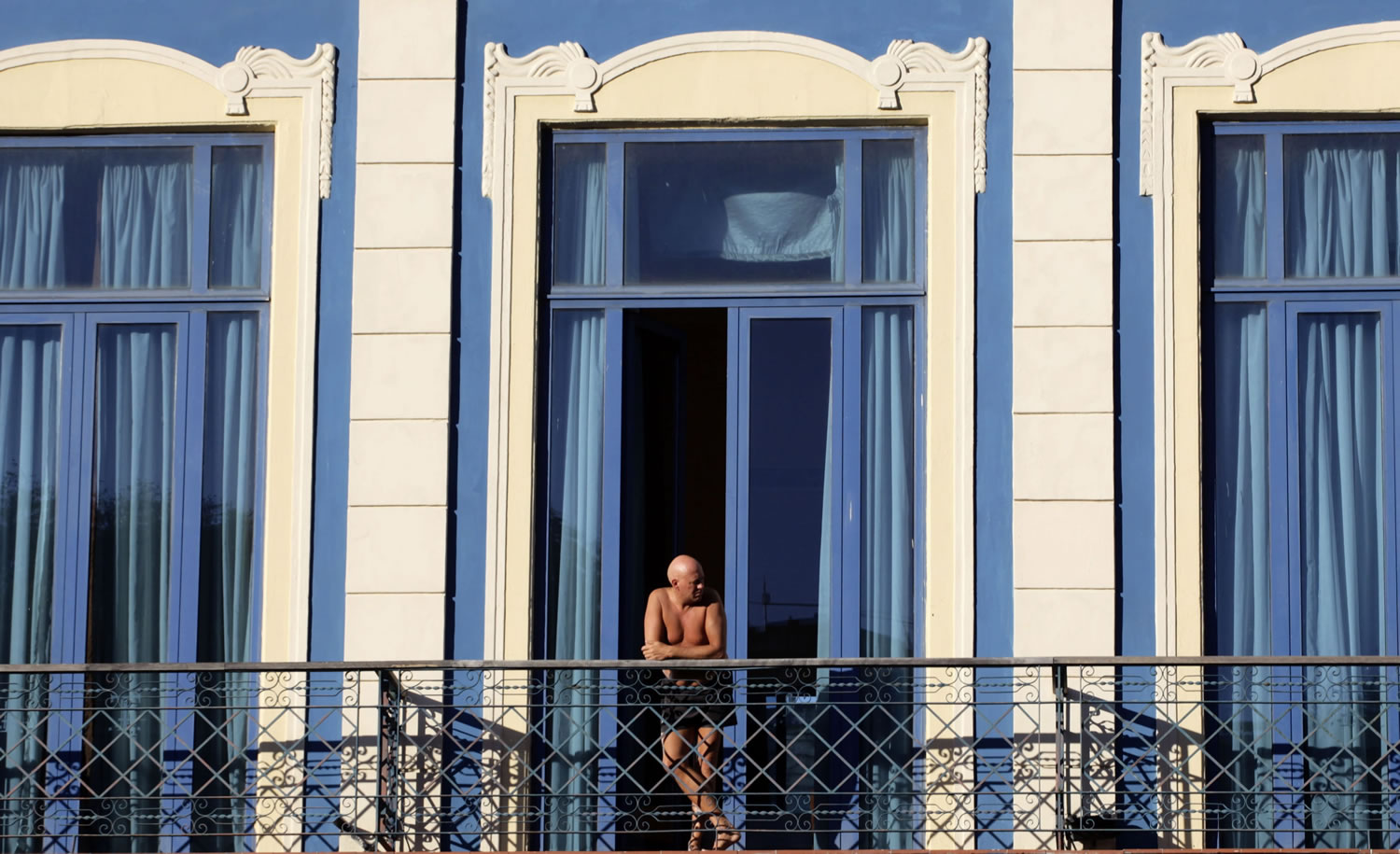 A tourist looks out from his hotel room's balcony in Havana, Cuba.