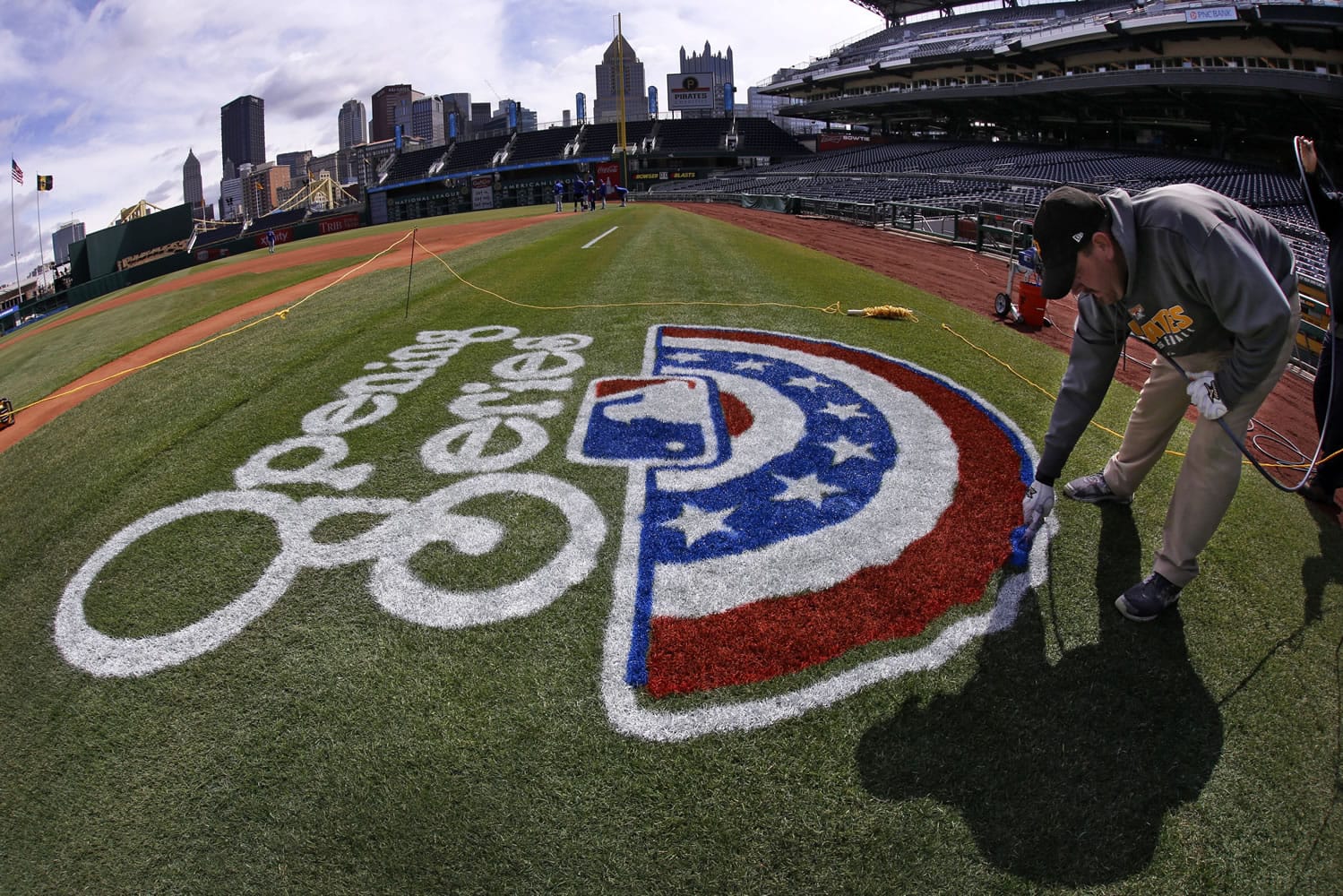 In this photo taken with a fisheye lens, Matt Gearhardt of the PNC ground crew paints the opening series logo on the field Sunday, March 30, 2014, in preparation for the Pittsburgh Pirates season opening baseball game, Monday, March 31 against the Chicago Cubs in Pittsburgh. (AP Photo/Gene J.