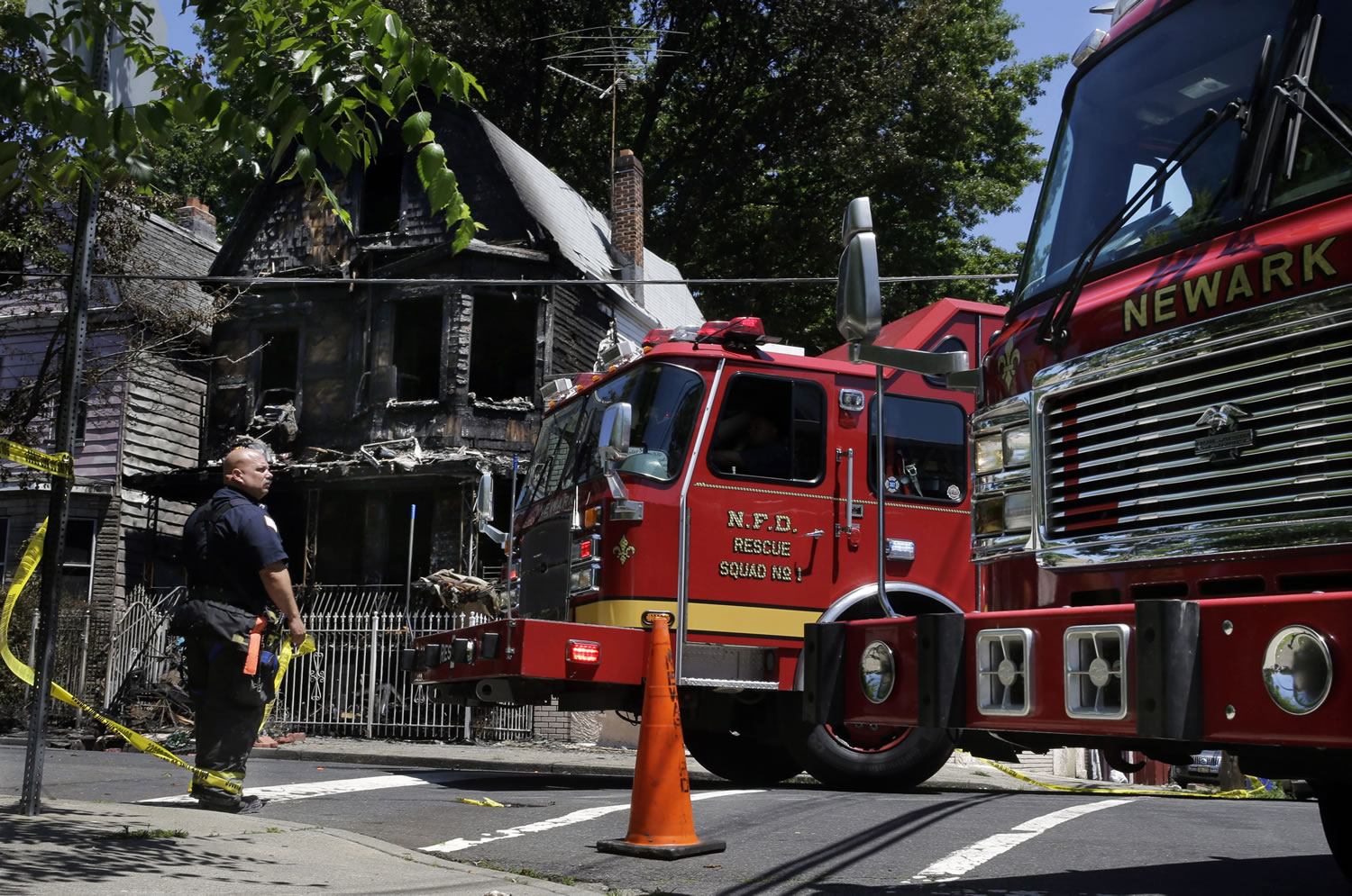 Firefighters work near the rubble of a burned-out home Sunday as they look for clues to a fire that authorities say killed six people in Newark, N.J.