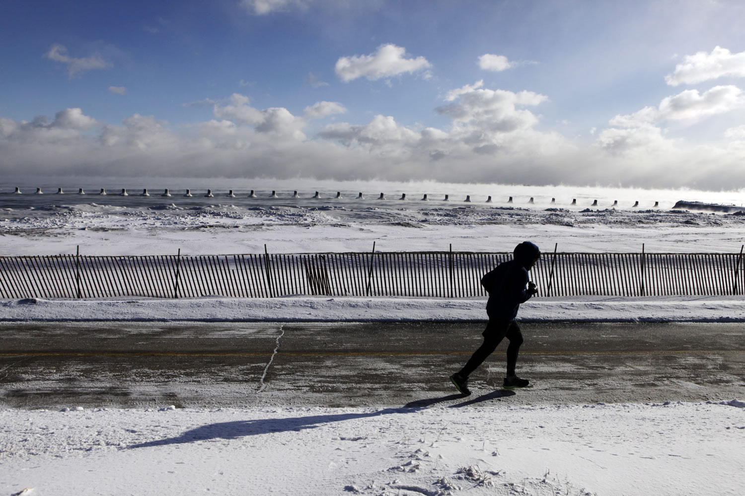 A runner jogs along the shore as steam rises up from Lake Michigan on Monday in Chicago.