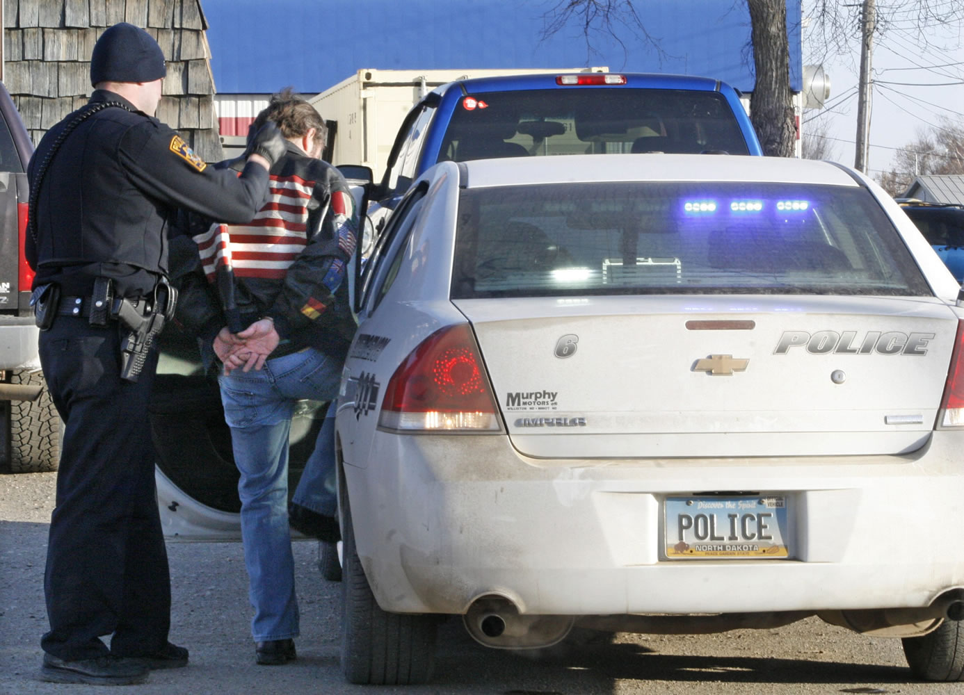 An officer guides a handcuffed man into a police car in Williston, N.D., on Feb. 28.