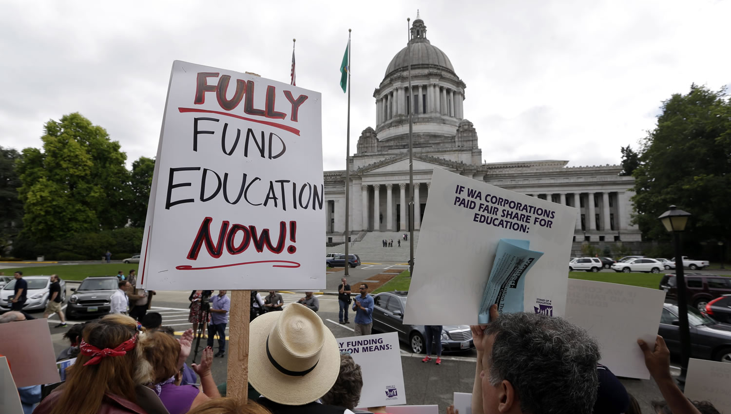 A small group of demonstrators stand on the steps of the Temple of Justice and in view of the Legislative Building as they advocate for more state spending on education prior to a hearing before the state Supreme Court on Wednesday in Olympia. The court ordered lawmakers to explain why they haven't followed its orders to fix the way Washington pays for public education.