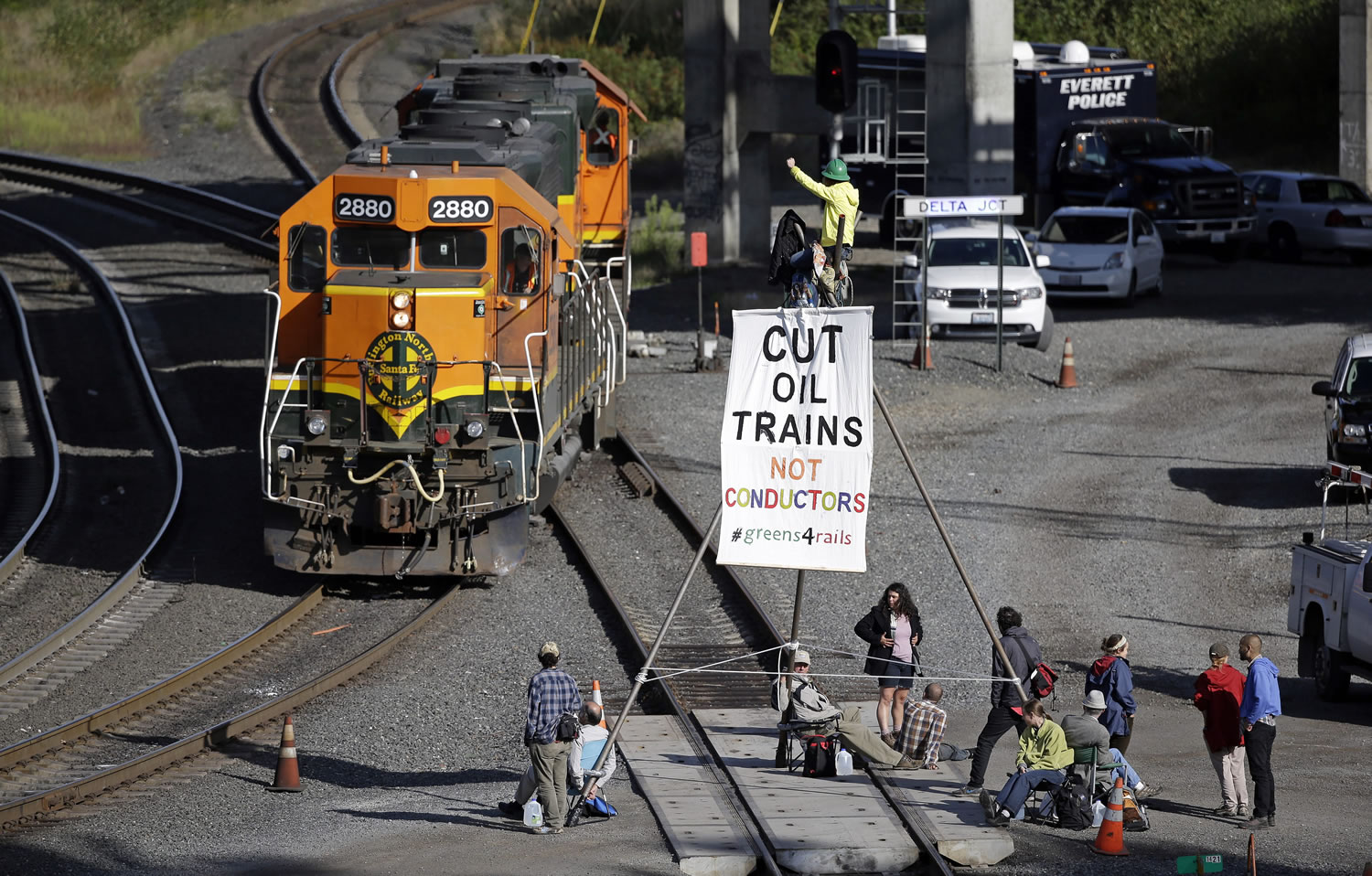 Abby Brockway waves from atop a tripod erected on train tracks to a pair of engines passing on an adjacent track Tuesday in Everett.