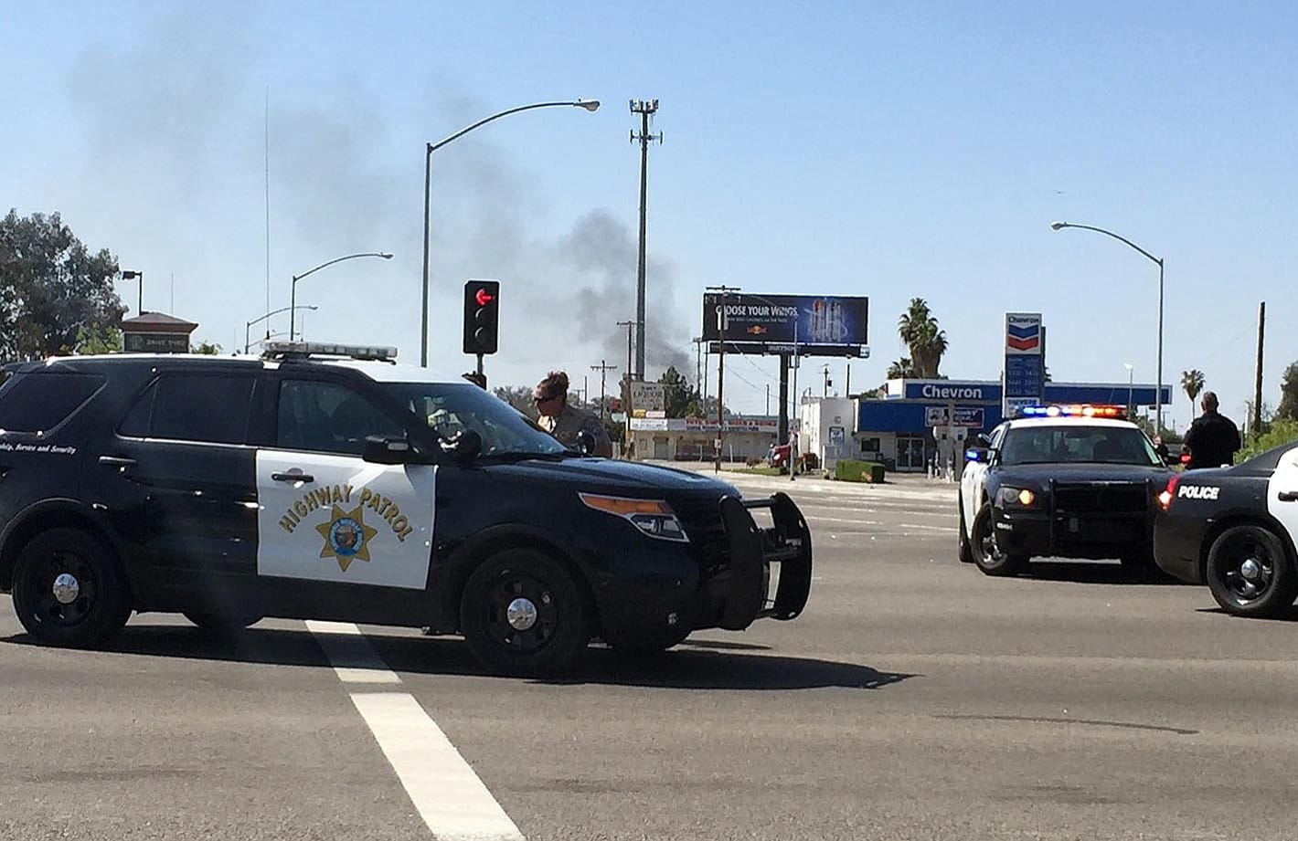 Highway patrol officers block off Herndon Avenue at Highway 99 where smoke can be seen at the fire from a gas line rupture in northwest Fresno, Calif.