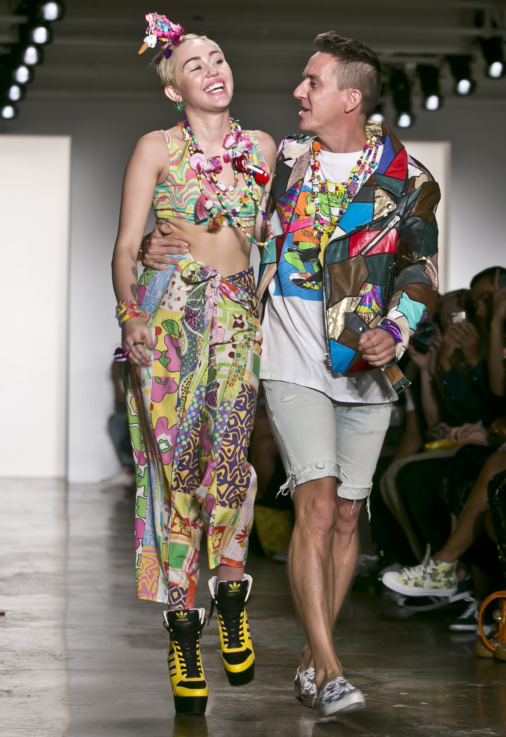 Entertainer Miley Cyrus, left, joins fashion designer Jeremy Scott for a walk on the runway after he showed his Spring 2015 collection during Fashion Week on Wednesday, Sept. 10, 2014 in New York.