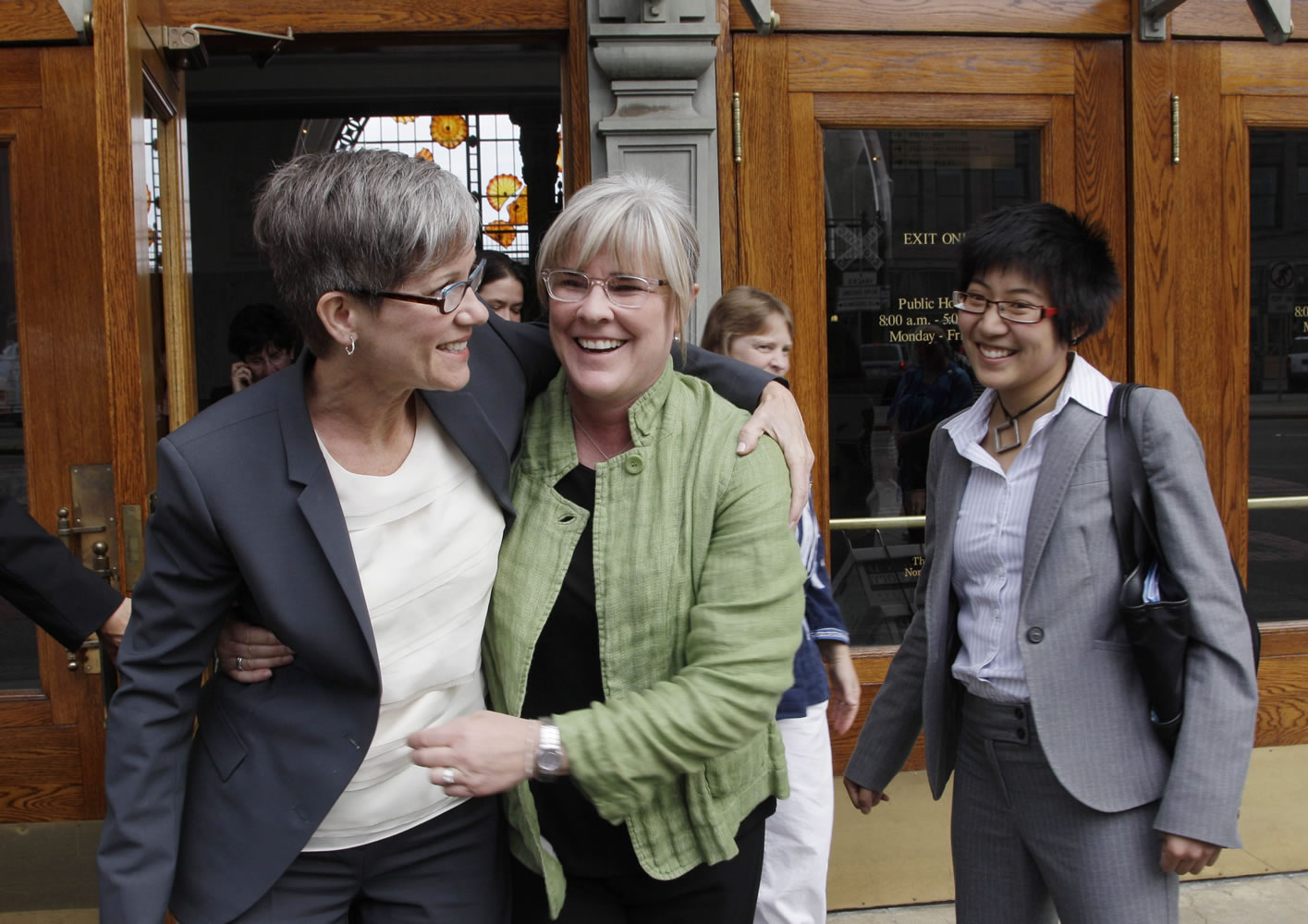 Sher Kung, right, a Seattle lawyer who worked with the ACLU, was killed in a bicycle accident Friday, Aug. 29, 2014.  In this photo taken Sept. 24, 2010, she looks on as Margaret Witt, center, and Witt's partner, Laurie McChesney, left, celebrate as they leave the federal courthouse in Tacoma, Wash.