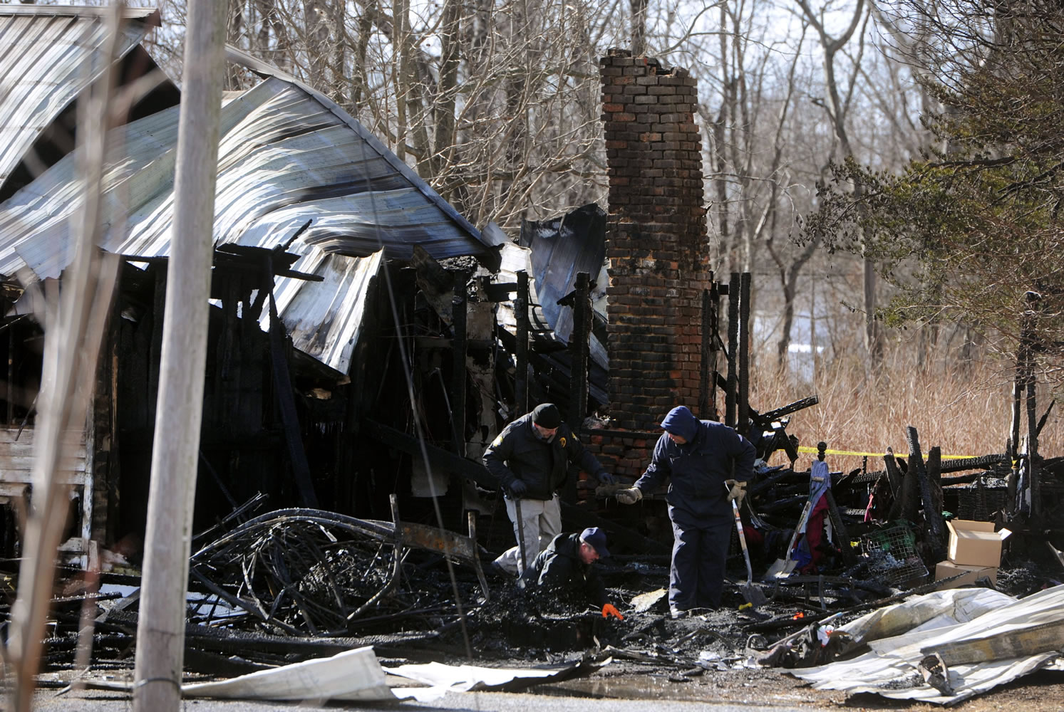 Alan Gregory, with the Kentucky Fire Marshal's office, at bottom, digs through debris Thursday after a house fire that killed nine members of an 11-member family  in Depoy near Greenville.