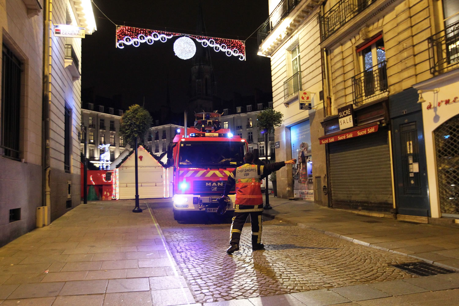 A rescue worker directs a fire brigade vehicle after a van crashed into a French Christmas market in Nantes, western France on Monday.