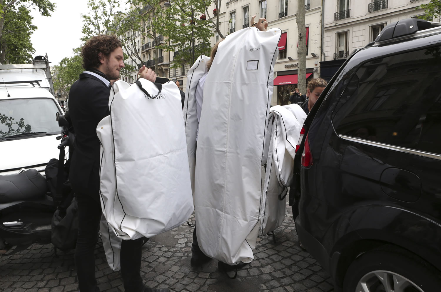Valentino fashion house employees leave Kanye West's apartment Wednesday after a fitting in Paris.