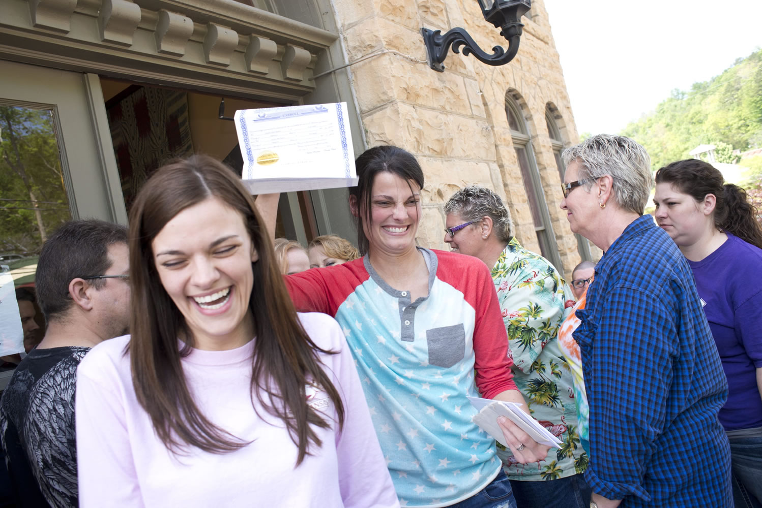 Kristin Seaton, center, of Jacksonville, Ark., holds up her marriage license as she leaves the Carroll County Courthouse in Eureka Springs, Ark., with her partner, Jennifer Rambo.
