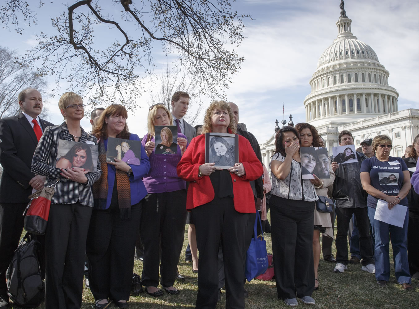 Families of victims of General Motors safety defects in small cars hold photos of loved ones as they gather at Capitol Hill in Washington.