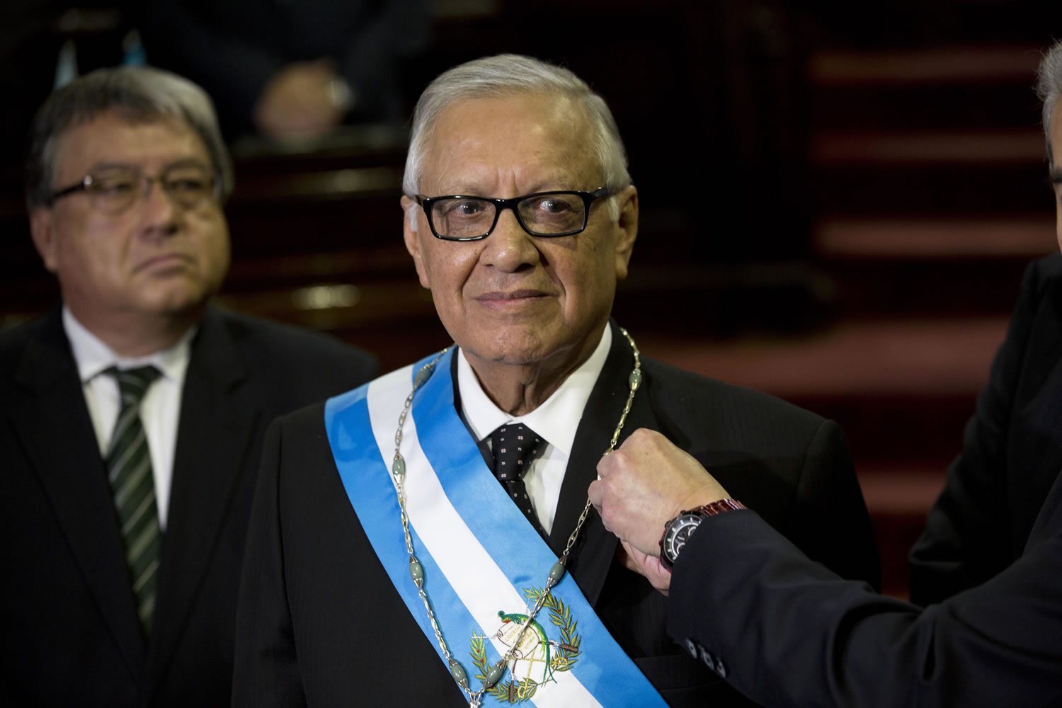 Guatemala's President Alejandro Maldonado stands still as Congress President Luis Rabbe pins on Maldonado's coat jacket the presidential pin, during the impromptu presidential swearing-in ceremony before Congress in Guatemala City, Thursday, Sept. 3, 2015. Maldonado was sworn in amid a corruption scandal that has caused a national political crisis. The conservative former judge will serve out the term of ex-President Otto Perez Molina, who resigned late Wednesday after a judge issued an order for his detention.