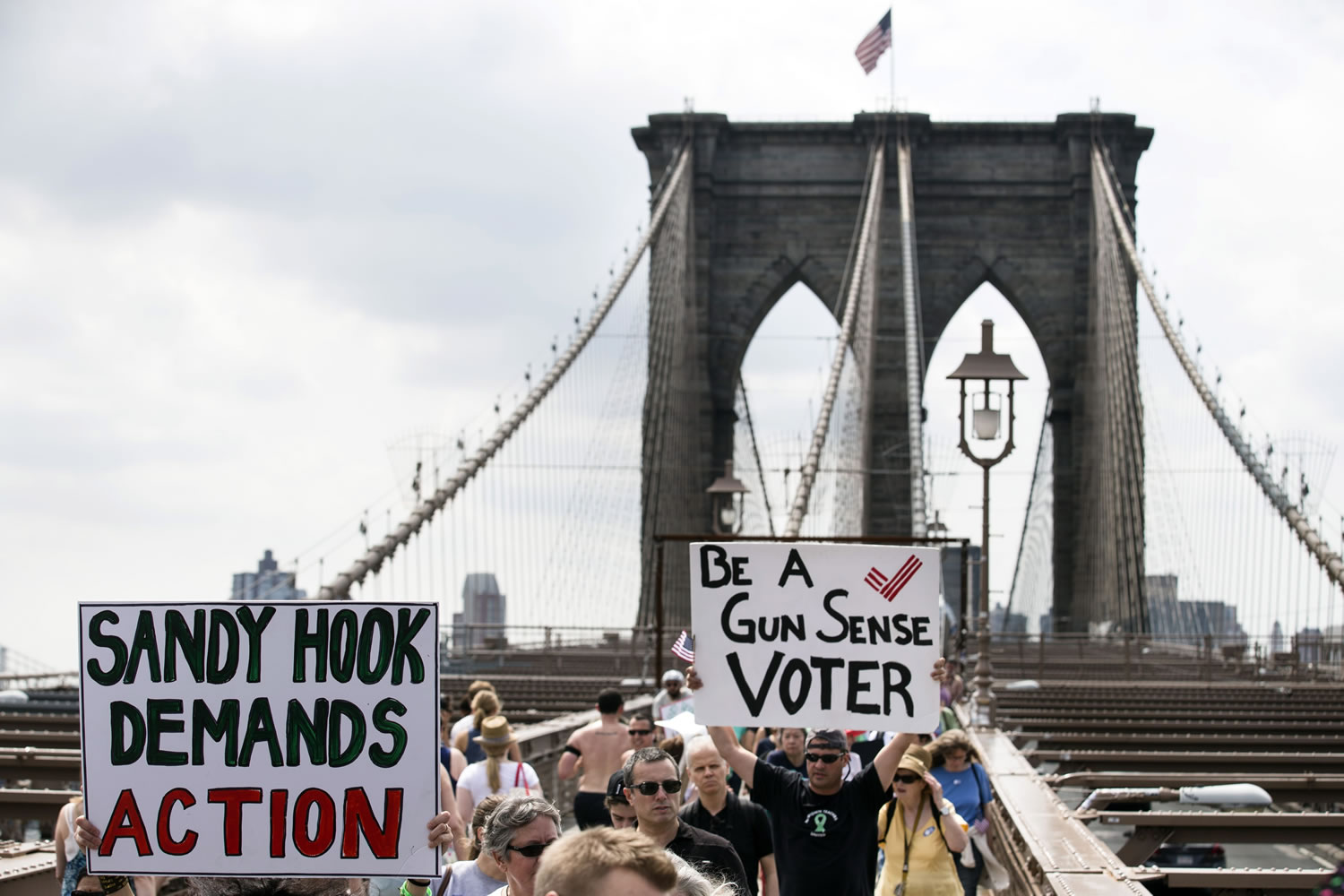 Demonstrators raise posters as they march across the Brooklyn Bridge to call for tougher gun control laws, Saturday in New York.