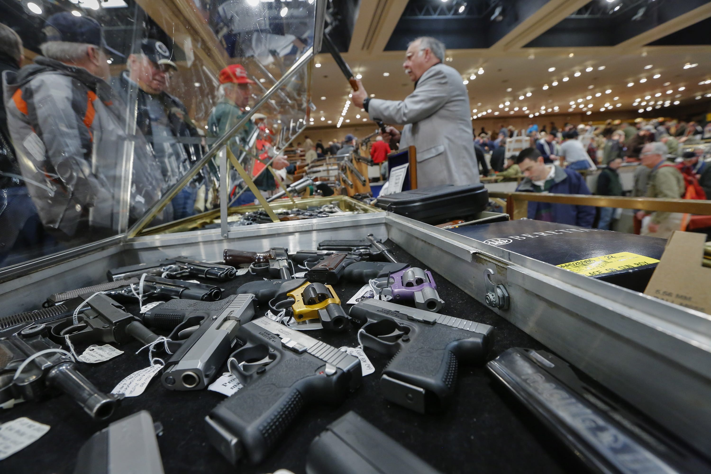 Handguns appear on display at the table of David Petronis of Mechanicville, N.Y., standing with rifle, who owns a gun store, during the heavily attended annual New York State Arms Collectors Association Albany Gun Show at the Empire State Plaza Convention Center in Albany, N.Y.