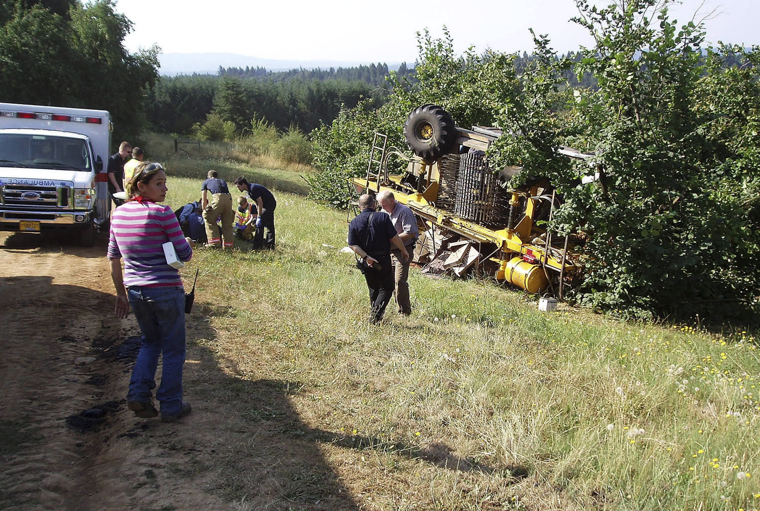 Clackamas County Sheriff's Office
Emergency crew officials work on the scene where a berry harvester flipped over at a farm near Sandy, Ore., on Monday. Two workers suffered broken legs and four others sustained minor injuries.