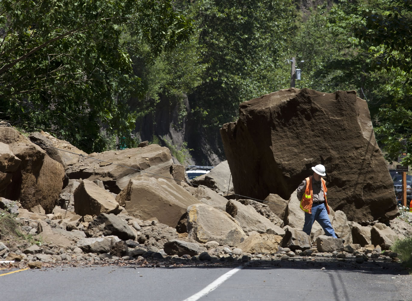 A worker makes his way through rocks Thursday on the Historic Columbia River Highway, east of Portland following a landslide.