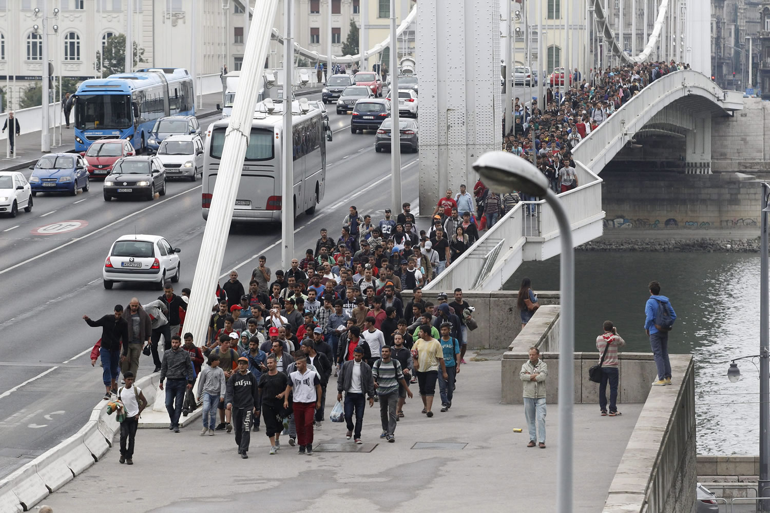 Migrants walk across Elizabeth Bridge over River Danube on their way to Austria from Keleti railway station in Budapest, Hungary, Saturday, Sept. 5, 2015, after the the Austrian and the German government allowed migrants staying in Hungary to enter their countries.