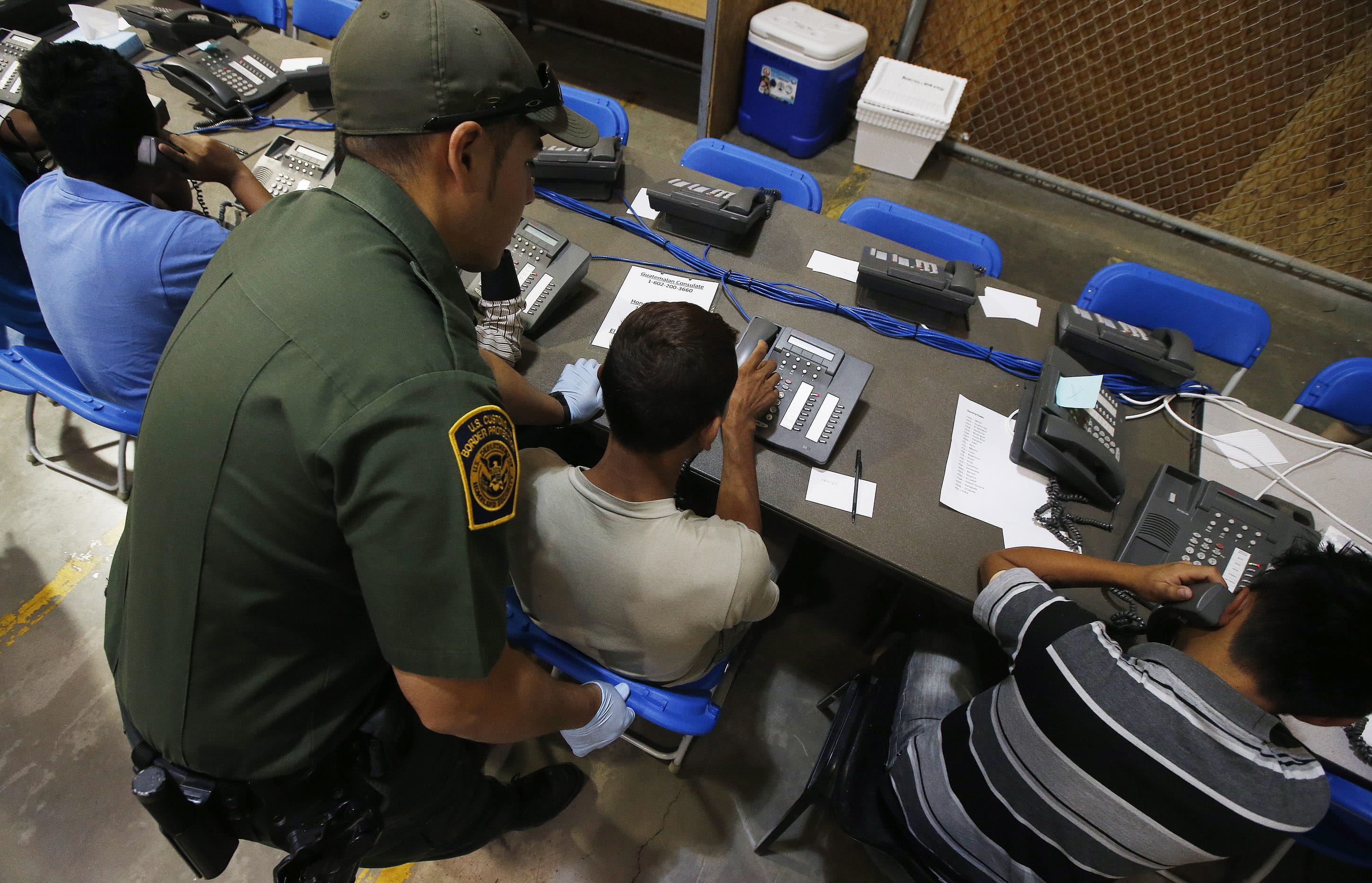 A U.S. Customs and Border Protection officer helps a few boys to make phone calls, some of the hundreds of mostly Central American immigrant children that are being processed and held at the U.S.