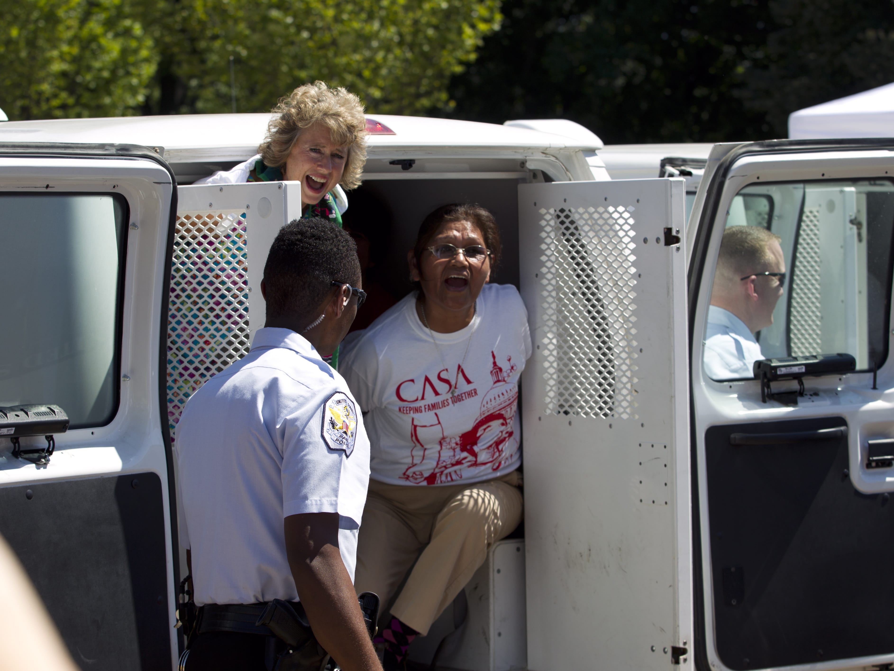 Demonstrators shout from a holding vehicle after being arrested Thursday outside the White House during a rally calling for President Obama to stop deportations.