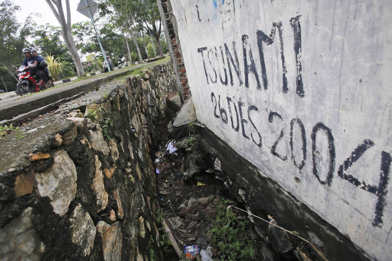 Motorists on Friday ride past graffiti with the date of the Indian Ocean tsunami, in Banda Aceh, Aceh province, Indonesia. The devastating Boxing Day tsunami in 2004 struck a dozen countries around the Indian Ocean rim, killing 230,000 people, most of them in Aceh.