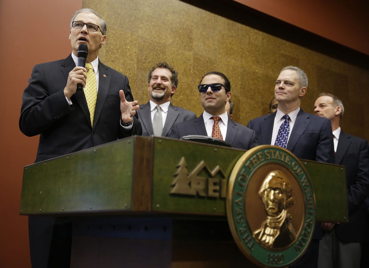 Gov. Jay Inslee, left, speaks Wednesday at REI's flagship store in Seattle.