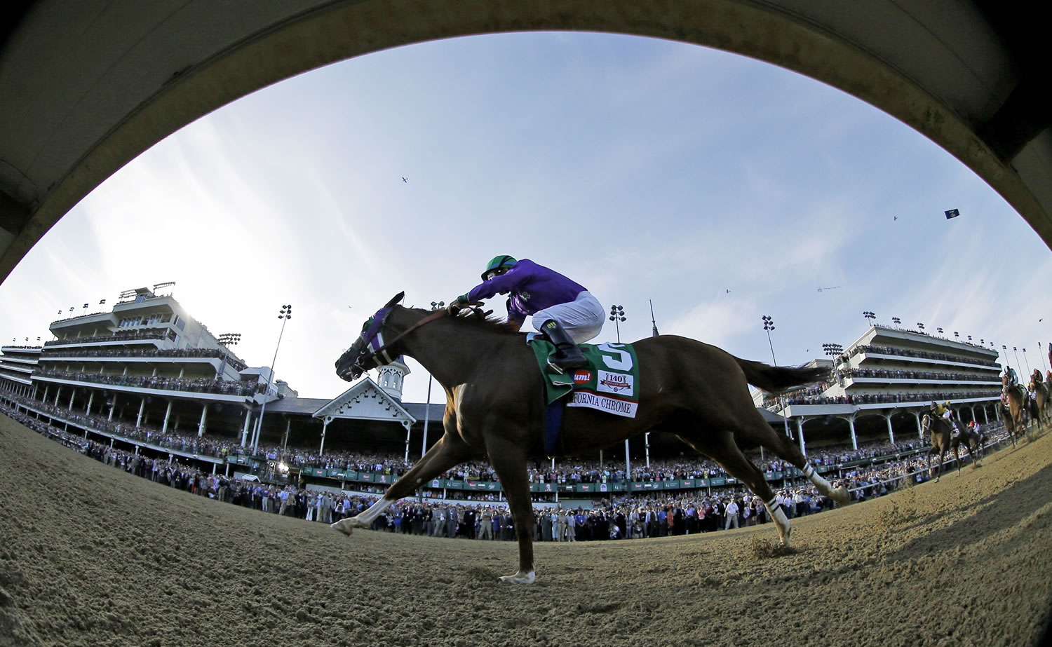 In this image taken with a fisheye lens, Victor Espinoza rides California Chrome to a victory during the 140th running of the Kentucky Derby horse race at Churchill Downs on Saturday in Louisville, Ky.