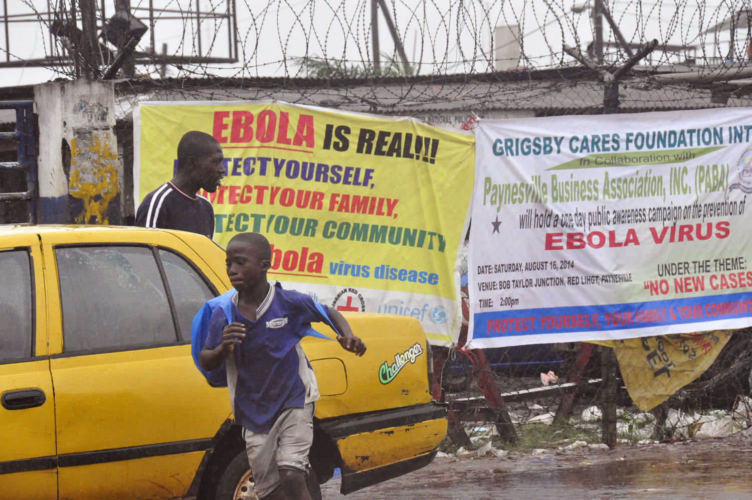 People pass by Ebola virus health warning signs Sunday in Monrovia, Liberia.