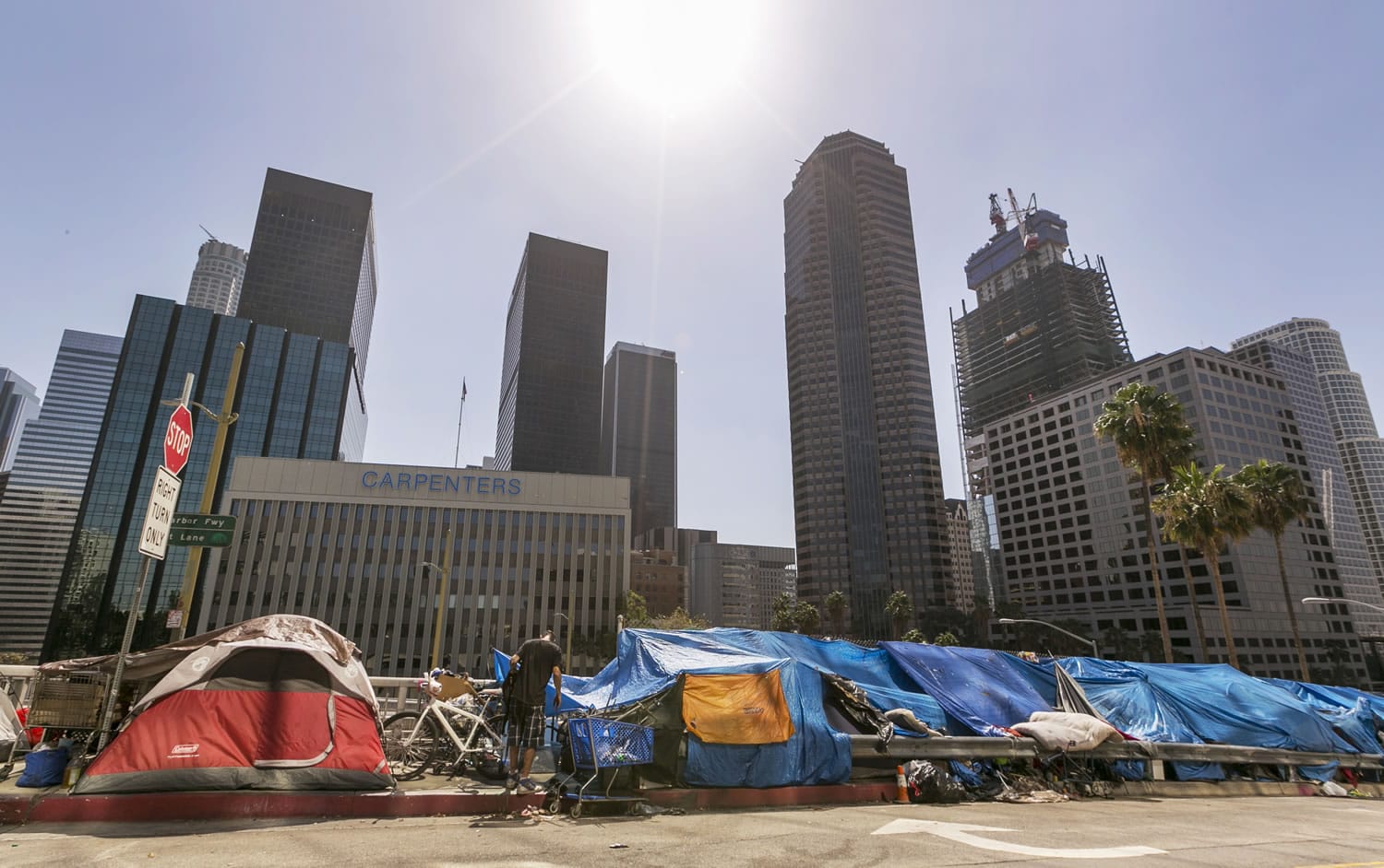 Tents used by the homeless line a downtown Los Angeles street with the skyline behind Tuesday, Sept. 22, 2015. Los Angeles officials say they will declare a state of emergency on homelessness and propose spending $100 million to reduce the number of people living on city streets.