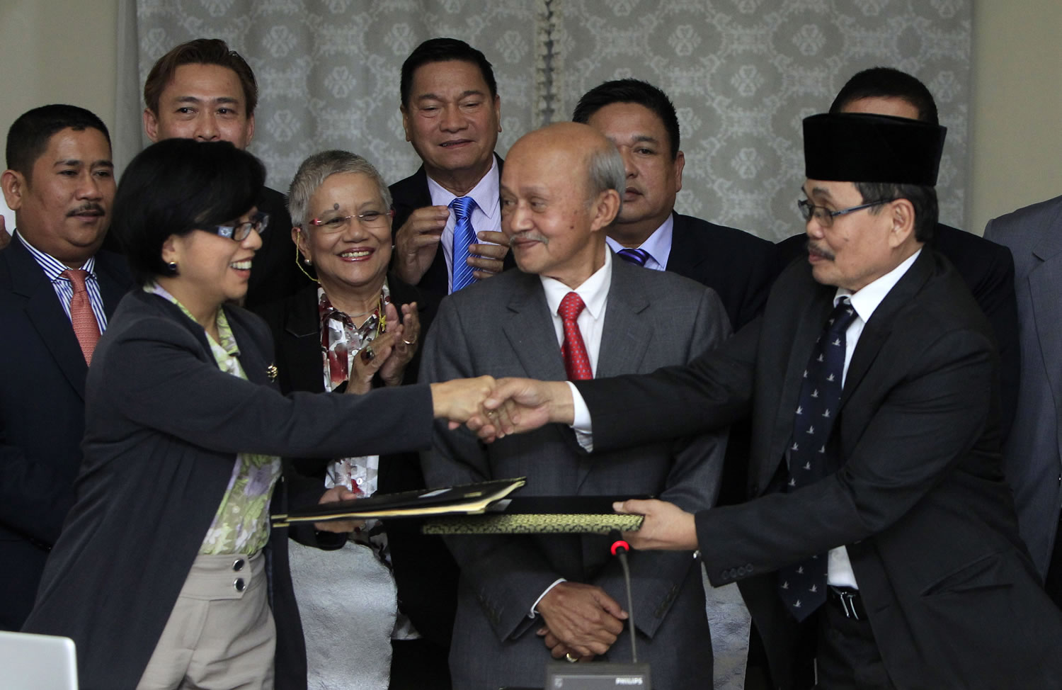 Miriam Coronel-Ferrer, front left, chairperson of Philippine Government Peace Panel, and Mohagher Iqbal, front right, chief negotiator for the Moro National Liberation Front, exchange signed documents Saturday as Malaysian facilitator Abdul Ghafar Tengku Mohamed, front center, witnesses after the 43rd GPH-MILF Exploratory Talks in Kuala Lumpur, Malaysia.