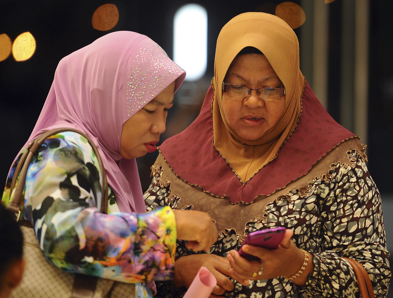 Family members of passengers aboard a missing Malaysia Airlines plane check a mobile phone before a briefing at a hotel in Putrajaya, Malaysia, on Tuesday.