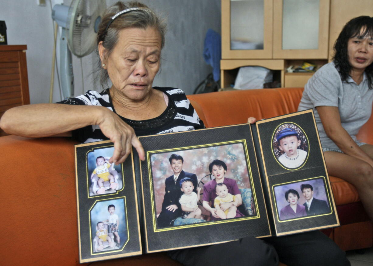 Suwarni, the mother of Sugianto Lo, who was onboard the missing Malaysia Airlines Flight 370 with his wife Vinny, shows her son's family portraits March 25 at her residence in Medan, North Sumatra, Indonesia. Indonesians Sugianto Lo and his wife, Vinny Chynthya Tio, were taking a short break away from their three children, their first in more than 17 years as parents. It was hard.