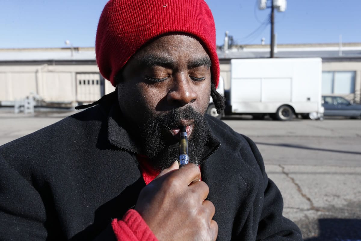 Homeless man Chris Easterling smokes legal hash oil from a vaporizer pen to ease the pain of his multiple sclerosis, in front of the Salvation Army shelter where he sleeps, in Denver.