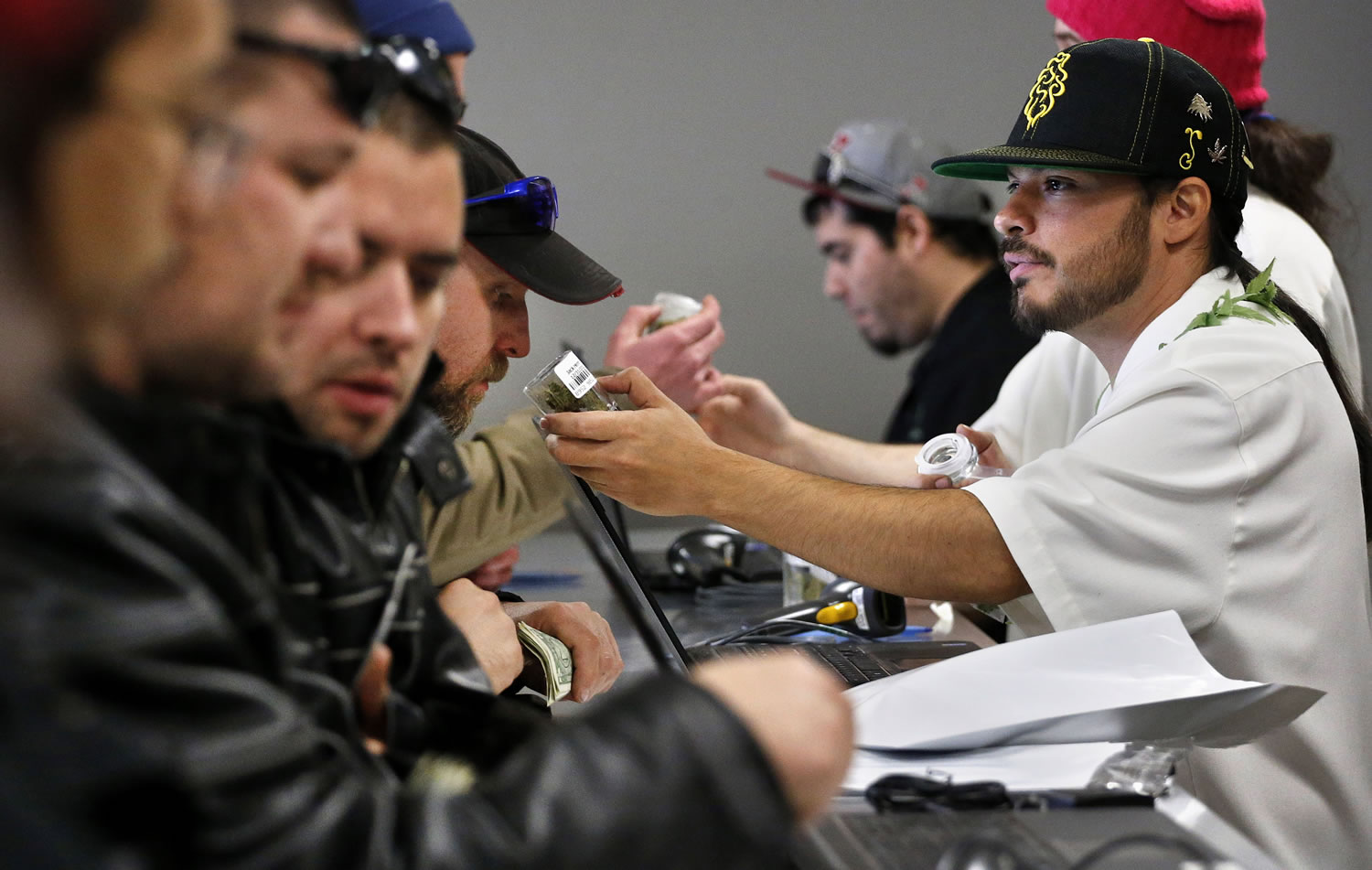 An employee right, helps a customer Jan. 1 at the crowded sales counter inside Medicine Man marijuana retail store in Denver. Colorado's top law enforcement official promises to vigorously defend the state's historic law legalizing marijuana after Nebraska and Oklahoma asked the U.S. Supreme Court to declare it unconstitutional, saying the drug is freely flowing into neighboring states.