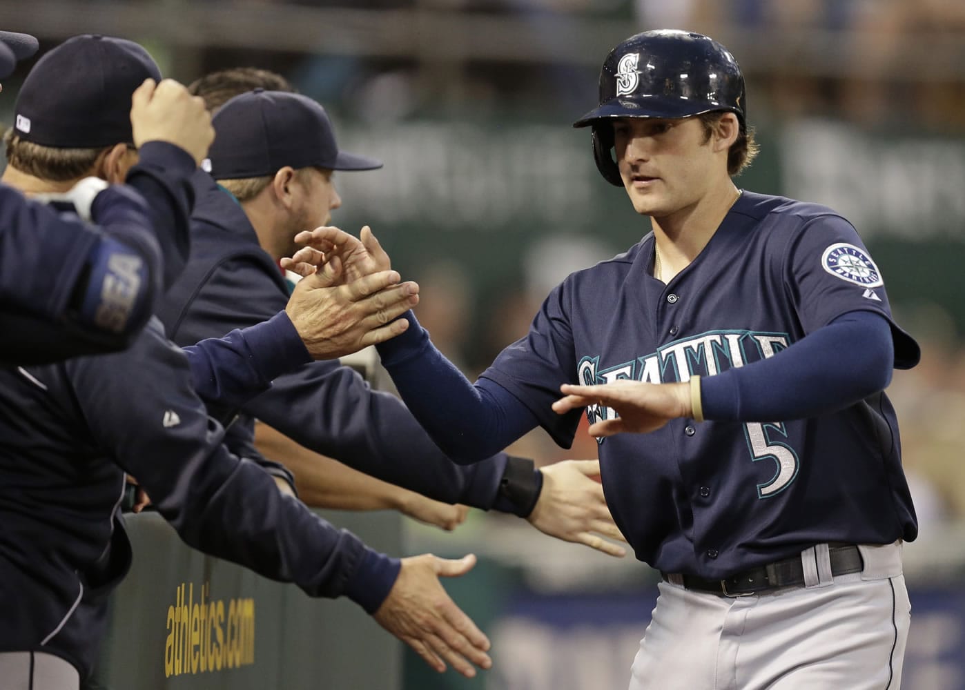 Seattle Mariners' Brad Miller, right, is congratulated after scoring against the Oakland Athletics in the third inning of a baseball game Tuesday, Sept. 2, 2014, in Oakland, Calif.