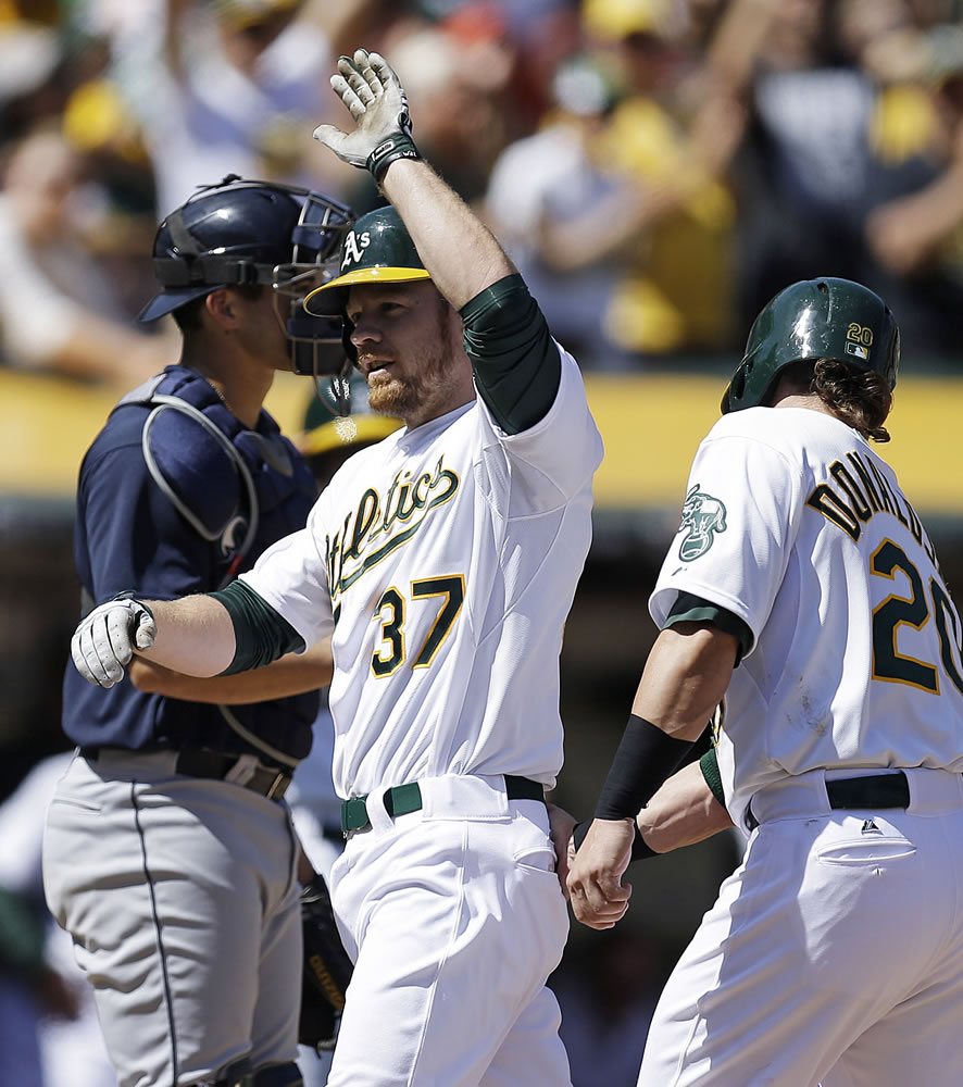 Oakland Athletics' Brandon Moss (37) is congratulated by Josh Donaldson, right, after Moss hit a three-run home run off Seattle Mariners' Erasmo Ramirez in the third inning of a baseball game Sunday, April 6, 2014, in Oakland, Calif.