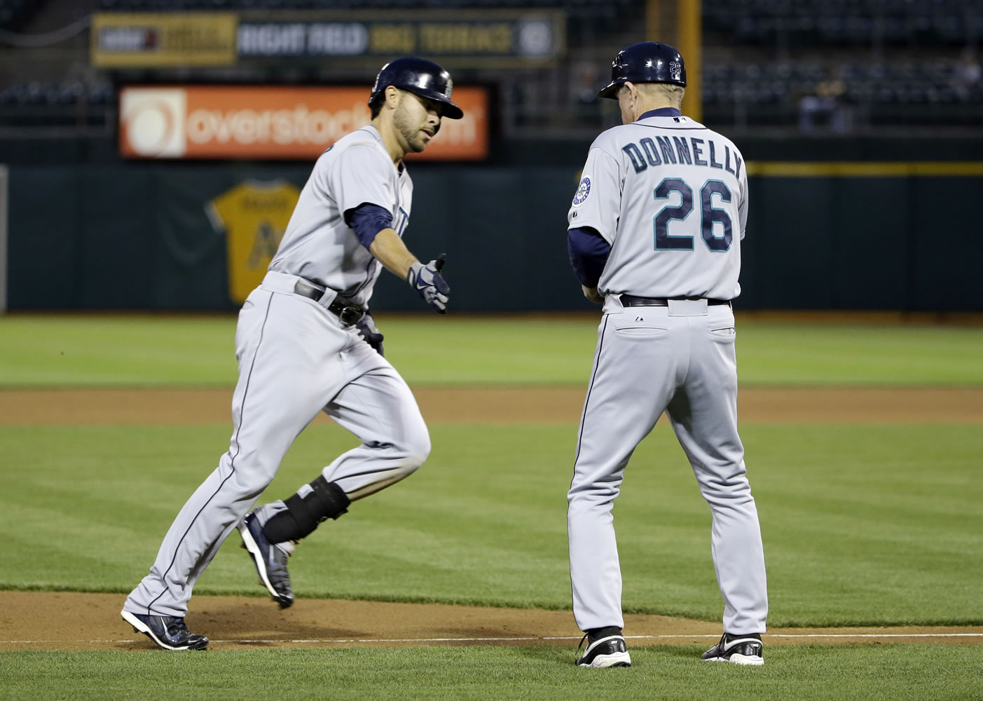 Seattle Mariners' Stefen Romero, left, shakes hands with third base coach Rich Donnelly after Romero's solo home run against the Oakland Athletics during the fifth inning of a baseball game on Monday, May 5, 2014, in Oakland, Calif.