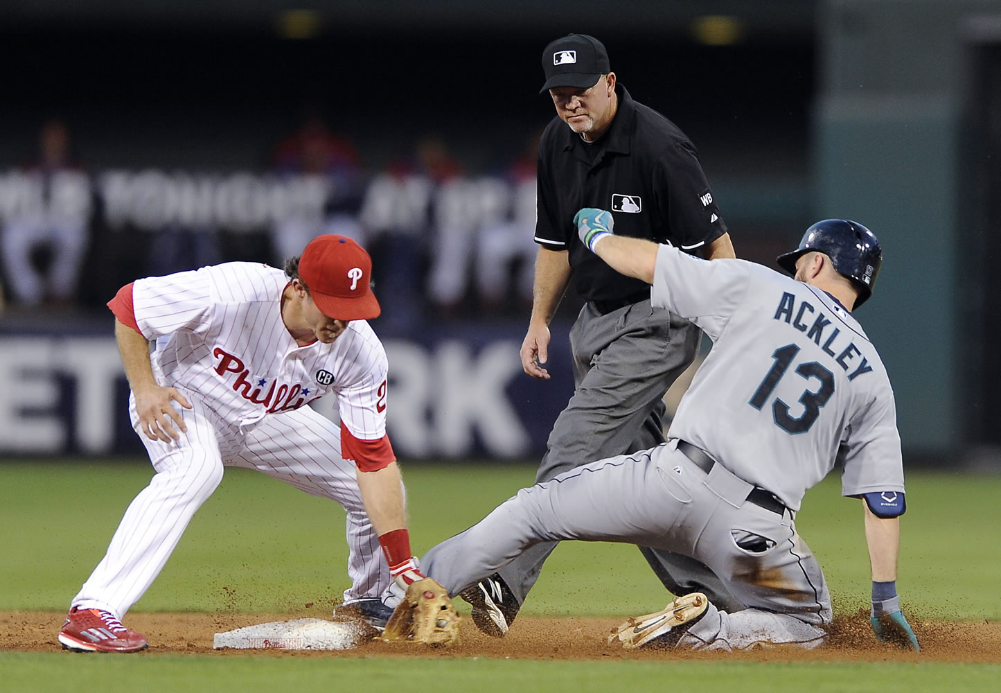 Seattle Mariners' Dustin Ackley (13) hits a double to left field and slides ahead of a tag from Philadelphia Phillies second baseman Chase Utley in the third inning of an interleague baseball game on Monday, Aug. 18, 2014, in Philadelphia.