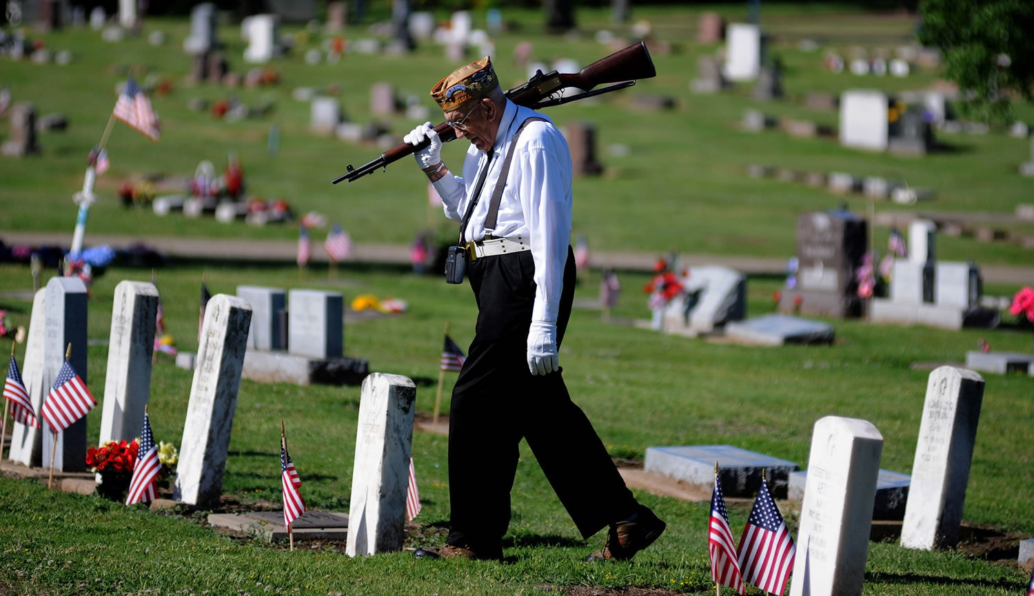 Bill Siebert, of Salina, a member of the VFW Post 1432 Firing Squad, walks through Gypsum Hill Cemetery to join his squad Monday in Salina, Kan.