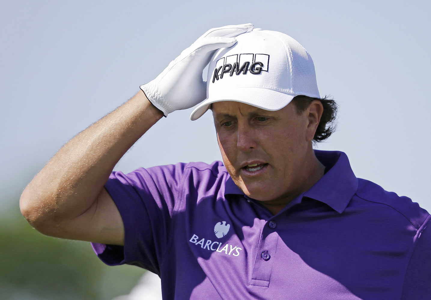 Phil Mickelson adjust his hat as he walks off the first tee during the third round of the Memorial golf tournament Saturday in Dublin, Ohio.  Mickelson says he's co-operating in an insider trading investigation involving him, investor Carl Icahn and Las Vegas gambler Billy Walters but maintains he did nothing wrong.
