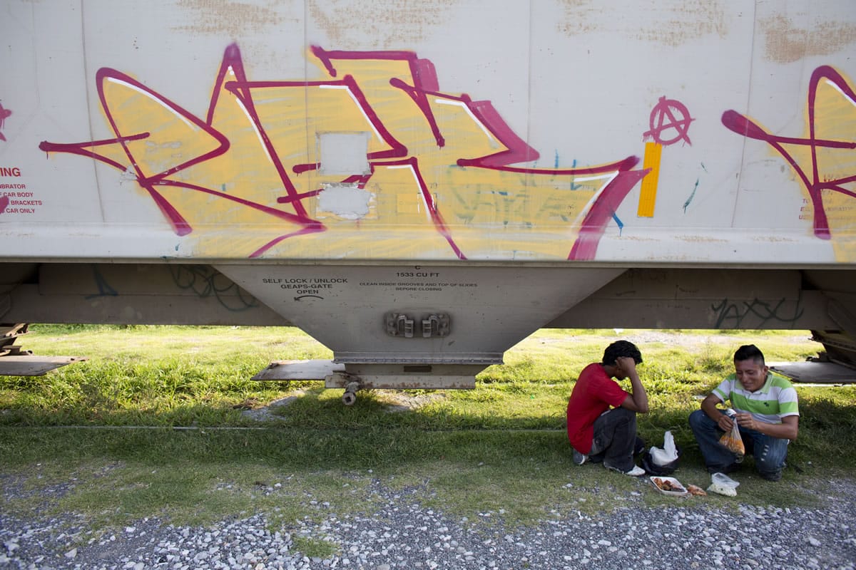 A pair of Central American migrants has lunch under a train Tuesday, Aug. 26 as they wait for it to depart from Arriaga, Mexico. A Mexican crackdown seems to be keeping women and children off the deadly train, known as &quot;The Beast,&quot; that has traditionally helped thousands of migrants head north. The city, once bustling with migrants waiting to board the train, emptied out almost overnight.