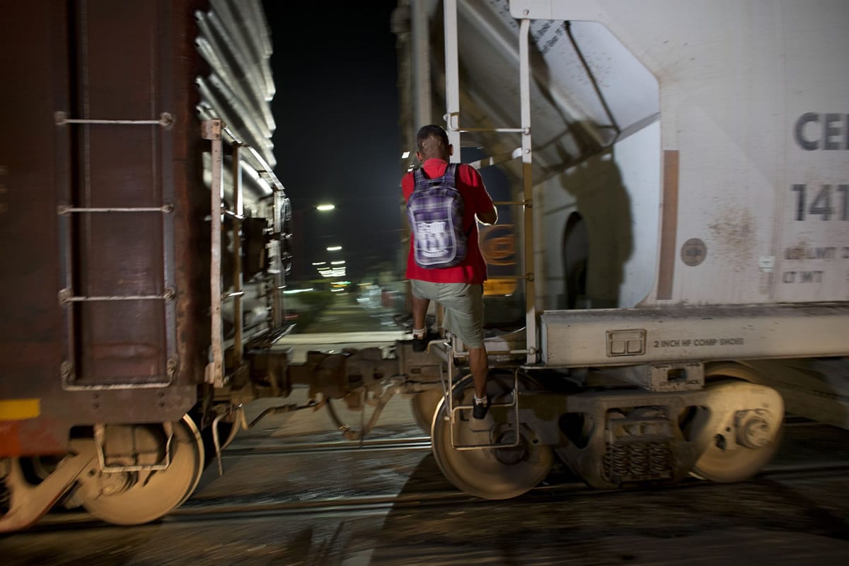 A Central American migrant jumps on a northbound freight train as it pulls out of the station in Arriaga, Mexico, late on Thursday.