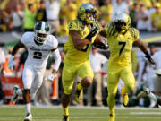 With Michigan State's Darian Hicks, left, in pursuit, Oregon's Devon Allen, center, runs to the end zone with teammate Keanon Lowe providing blocking during the 2nd quarter of their college football game in Eugene, Oregon, Saturday Sept. 6, 2014.