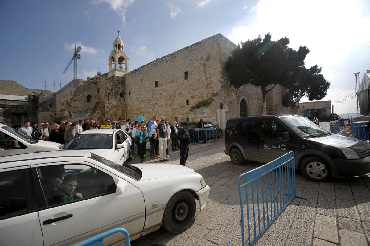 Tourists walk and cars drive past the Church of the Nativity in Bethlehem, West Bank.